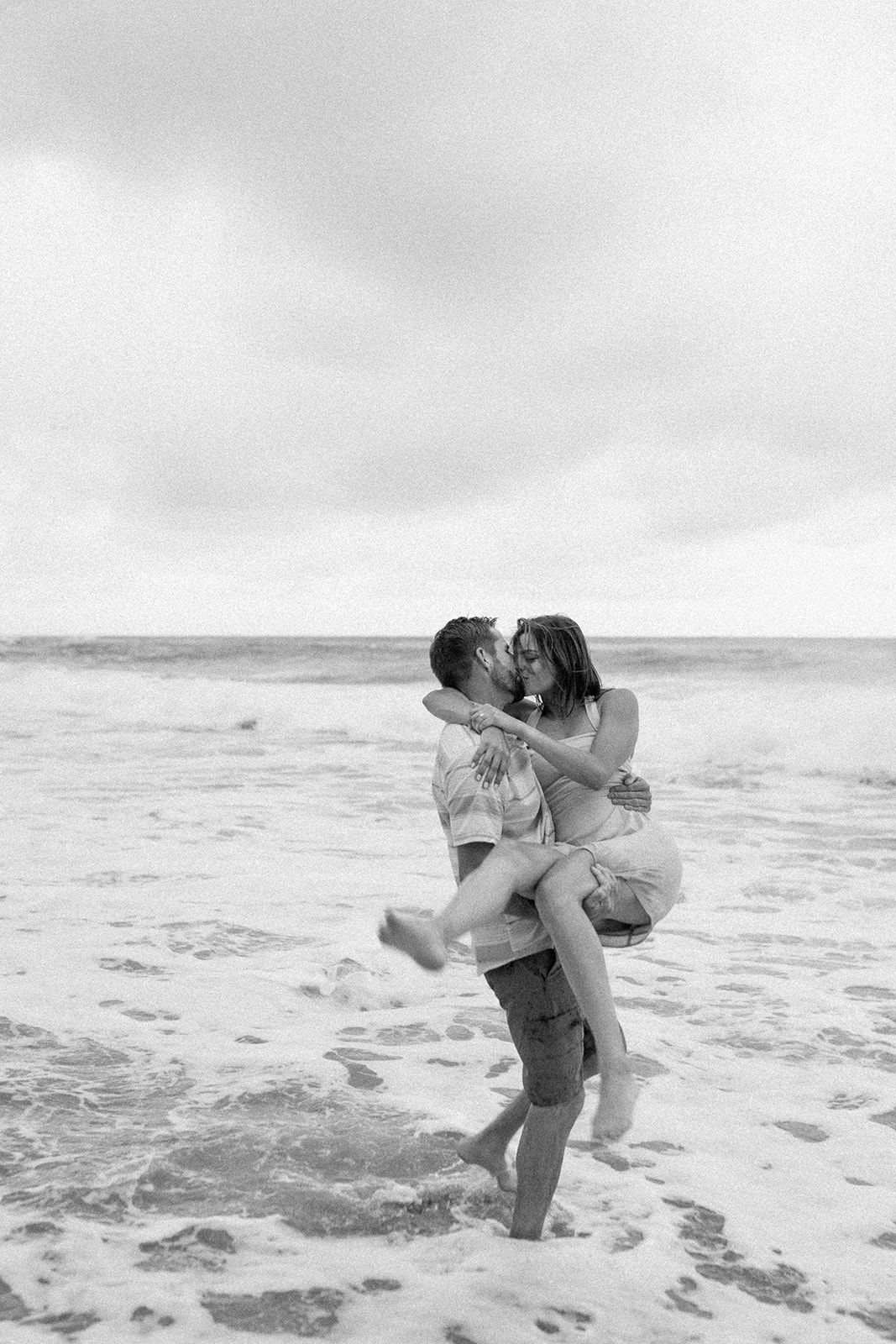 Boyfriend is holding girlfriend and standing in the ocean in Kauai, Hawii