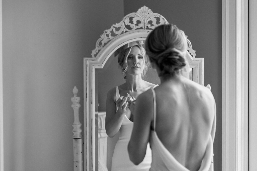 bride getting ready in front of the mirror for her wedding day