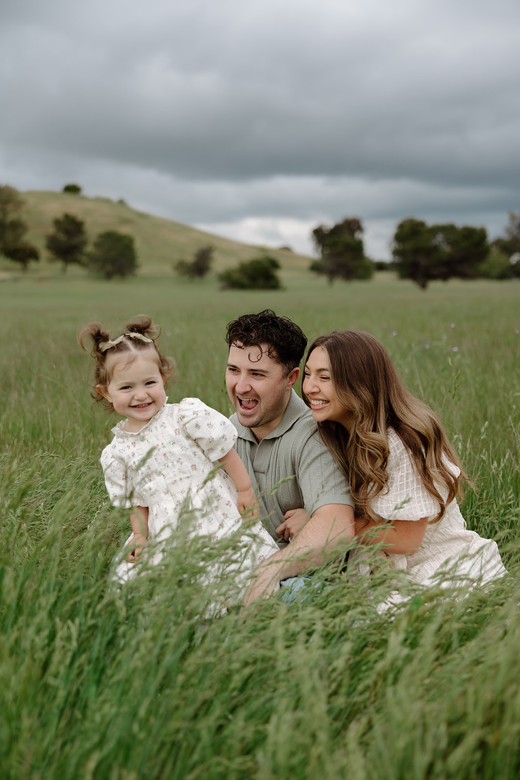 family photos in san jose california, family of three with a mom and dad and their 2 year old daughter wearing space buns and a white dress