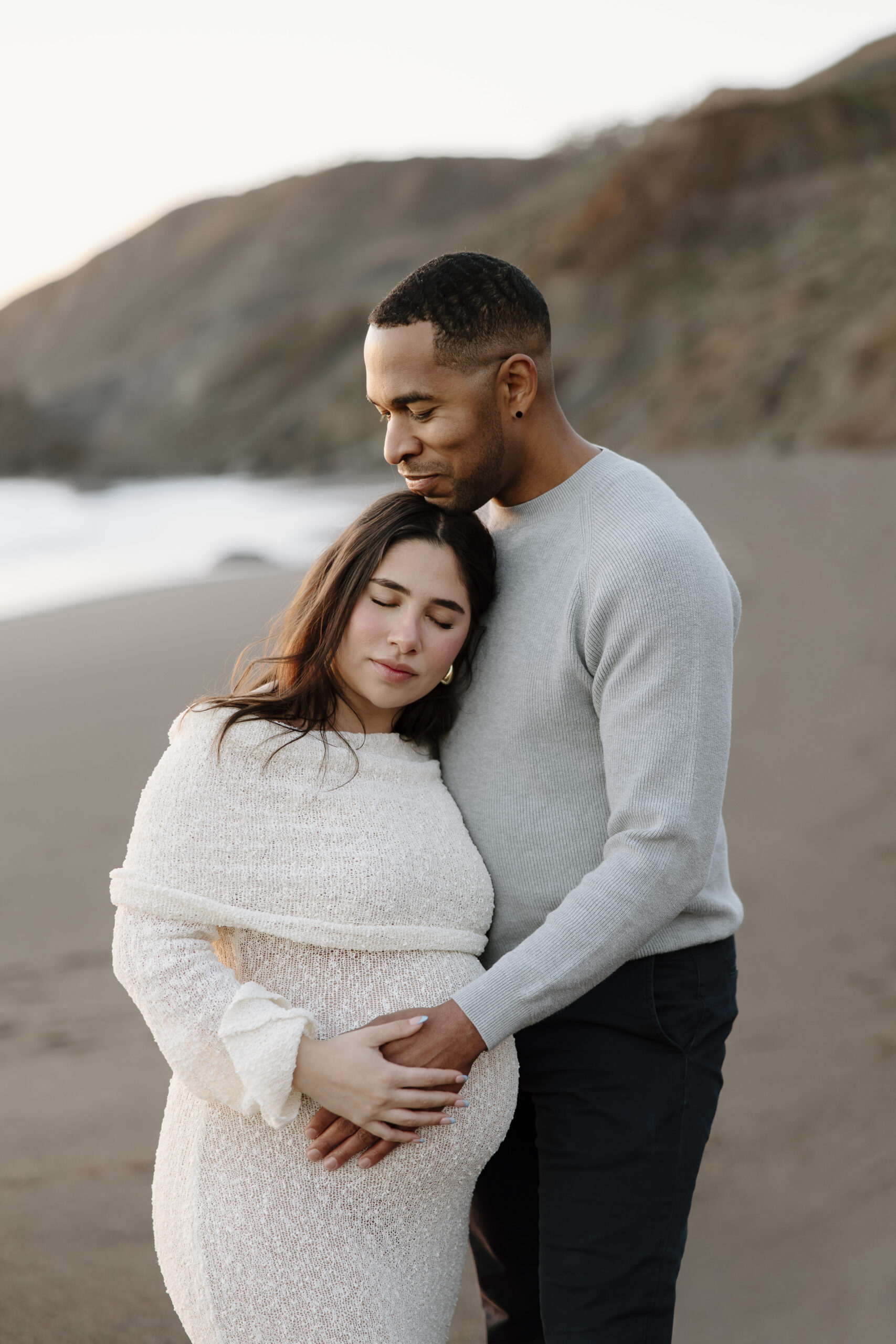 black sands beach maternity photos of couple standing and hugging